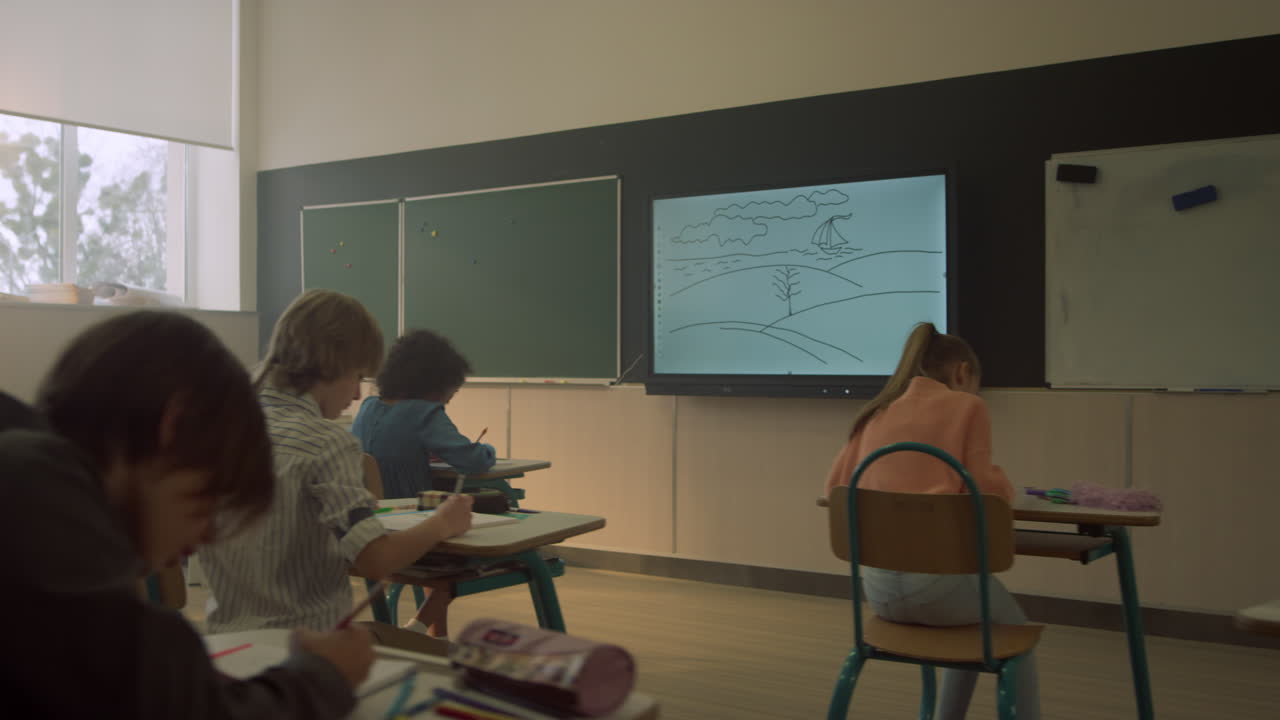 escolares sentados en los escritorios en el aula durante la lección en la escuela primaria