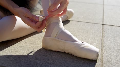 female ballet dancer tying the ribbon on her ballet shoes 4k