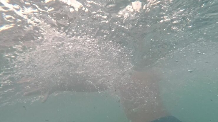 Underwater footage of caucasian kid swimming and getting out of the sea 60fps