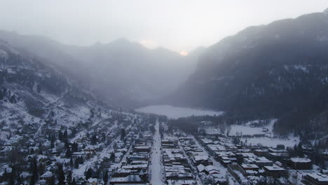 Filmische-Drohnenaufnahme-Aus-Der-Luft-Des-Skigebiets-Telluride-Mountain-In-Der-Innenstadt-Von-Colorado,-Neuschnee-Und-Nebel-Der-Malerischen-Berglandschaft-Und-Historischen-Gebäuden,-Lastwagen-Und-Autos-Am-Morgen,-Winter,-Rückwärtsbewegung