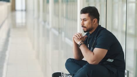 Upset-doctor-sitting-on-the-floor-in-the-corridor