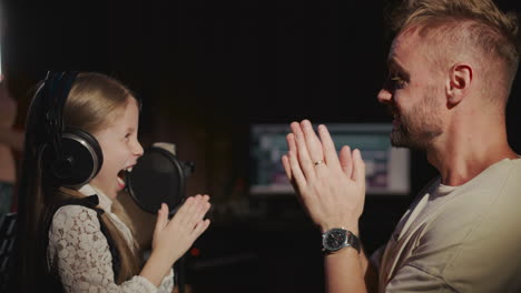 una joven cantando en un estudio de grabación con un productor