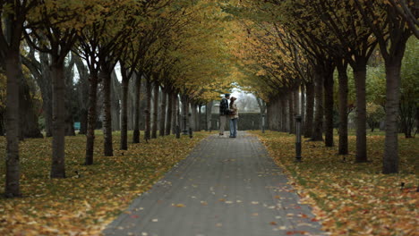 Romantic-young-lovers-kissing-with-holding-hands-in-beautiful-autumn-park.