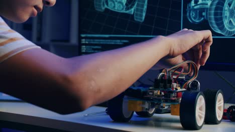 Asian teenager doing open-source hardware and software robot homework project in house