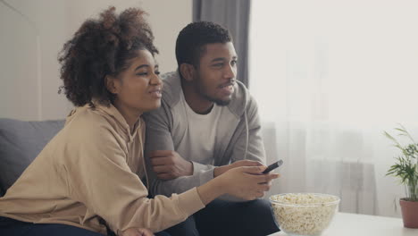 young couple picking something to watch on tv with the remote control 1