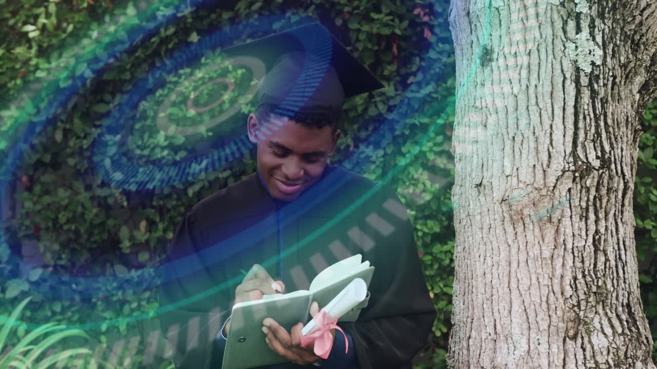 Male graduate pausing at tree, causing teal overlay, pulling notebook and writing graduation notes