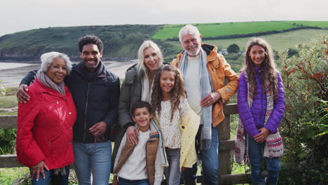 portrait of active multi-generation family by gate walking along coastal path in fall or winter