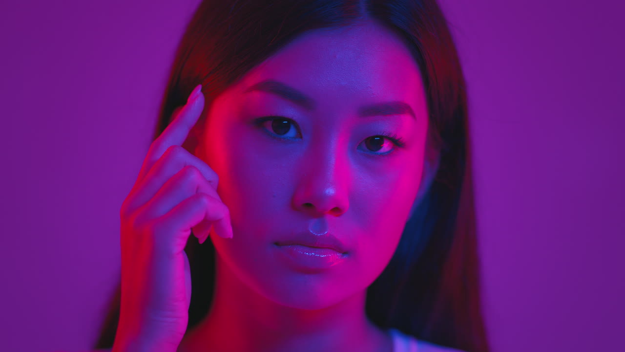 Close-up portrait of an Asian woman in vibrant neon lighting