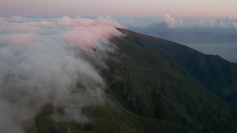 clouds forming above mountains and flowing over edge in madeira at dawn