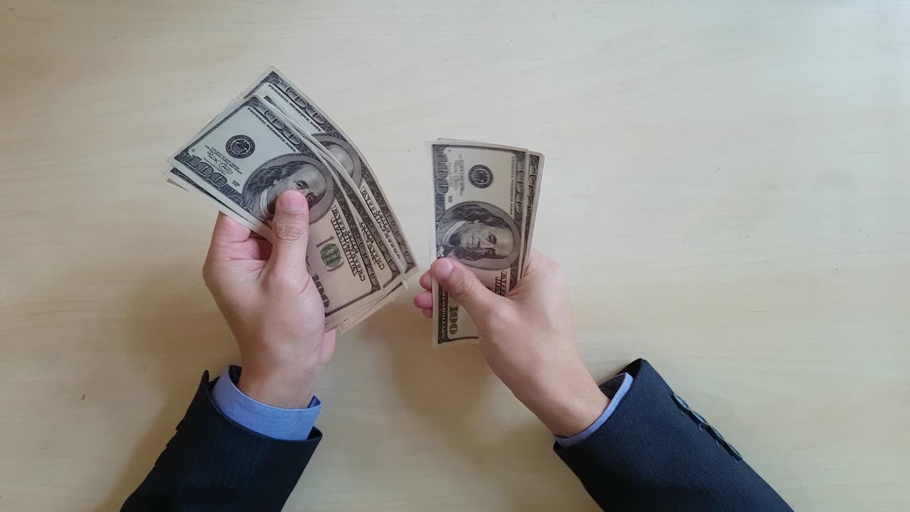 las manos de un hombre de negocios cuentan billetes de cien dólares en la oscuridad.