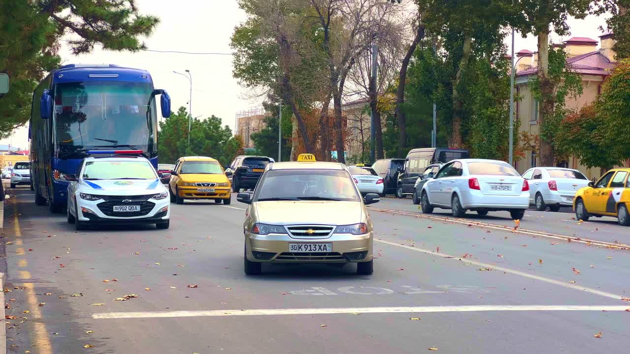 Urban Street Scene with Diverse Traffic Including Taxis, Bus, and Police Car