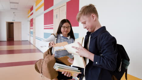 students exchanging books in a school hallway
