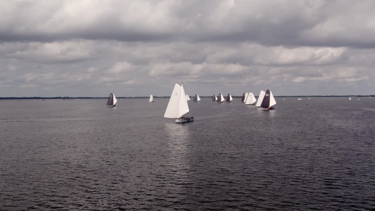 Luftaufnahme traditioneller Segelboote auf dem Tjeukemeer See während einer Veranstaltung in Echtenerbrug, Niederlande, mit atemberaubendem Sonnenaufgangslicht, ruhiger Atmosphäre und hochwertigen Drohnenaufnahmen, die die natürliche Schönheit hervorheben.