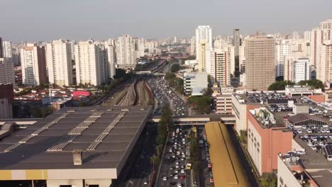 Una-Toma-De-Drones-De-Una-Ciudad-Ocupada-Donde-Se-Ve-Una-Carretera-Asfaltada-Y-Se-Ven-Edificios-De-Gran-Altura-A-Ambos-Lados-De-La-Carretera