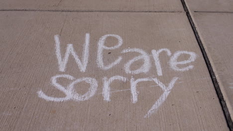 We-are-sorry-message-written-in-sidewalk-chalk