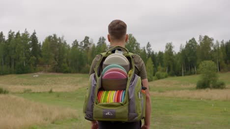 Golfista-De-Disco-Caminando-Por-El-Campo-Con-Una-Bolsa-Trasera-Llena-De-Discos