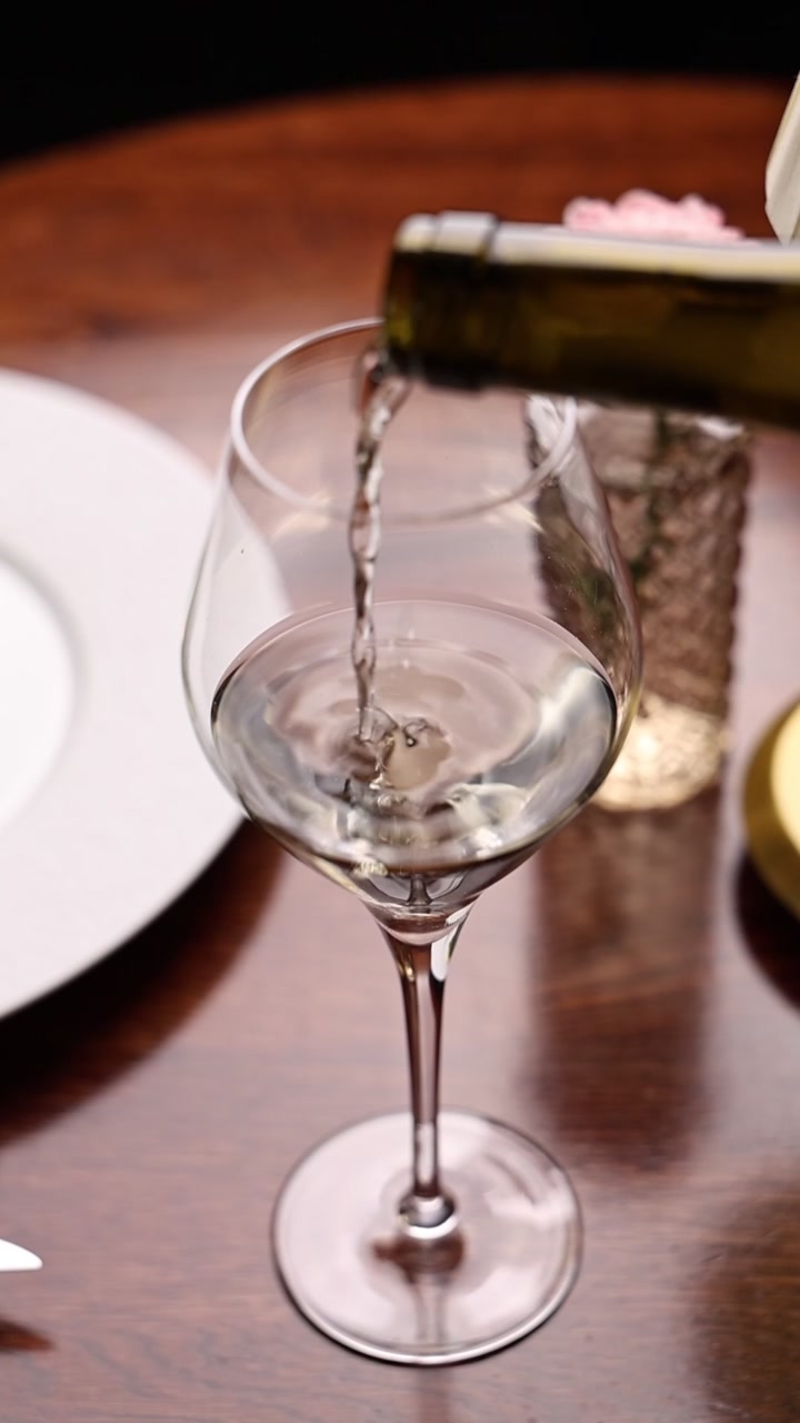 Vino bianco versato in un bicchiere a un tavolo di ristorante