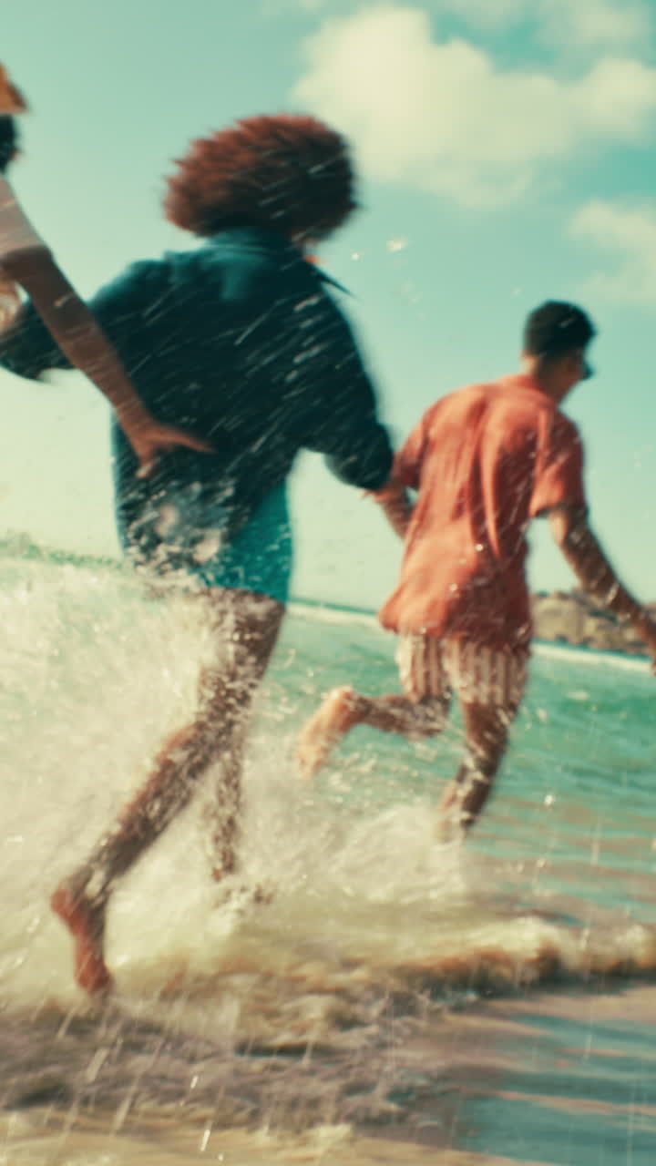 Group of Young People Running and Splashing in Ocean Water at the Beach