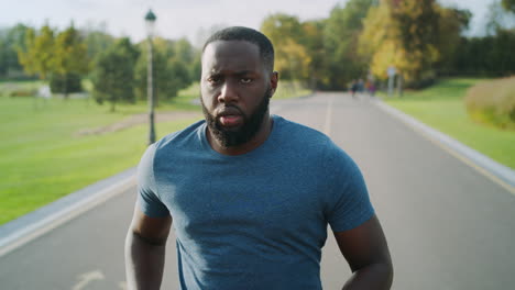 concentrated sportsman jogging on asphalt road. bearded guy training outdoors