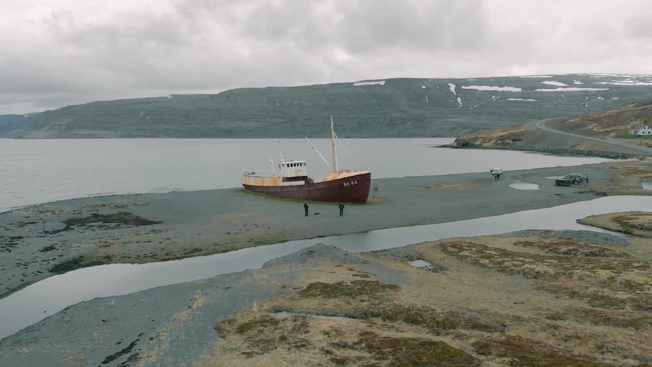 Luftfoto af et forladt, rustent skibsvrag på en øde islandsk strand