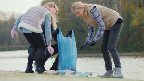 a woman with children picks up trash on the lake volunteers collect plastic waste