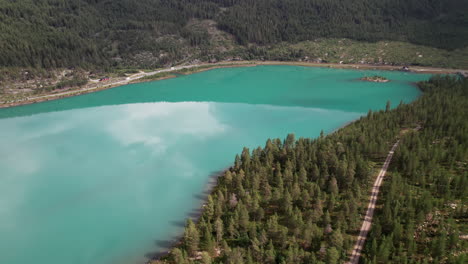 impresionante vista aérea de un lago verde, azul turquesa con una hermosa costa en noruega, reflejos en el agua tranquila, carretera forestal noruega, algo de tráfico en el fondo, escandinavia