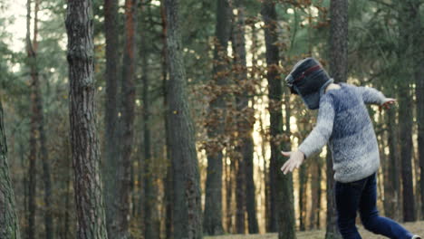 Little-Caucasian-boy-dreamer-of-being-a-pilot-having-fun-and-running-in-circles-in-the-wood-with-hands-open