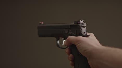 single hand gently lowering 9mm handgun