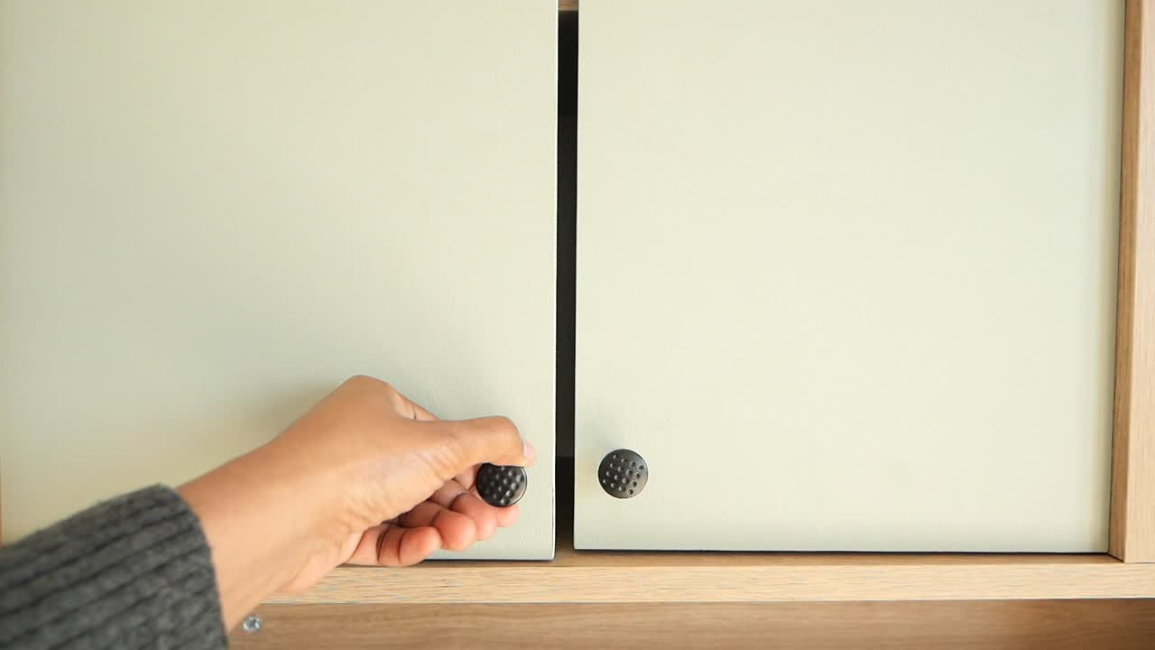 Person opening a light beige cabinet door