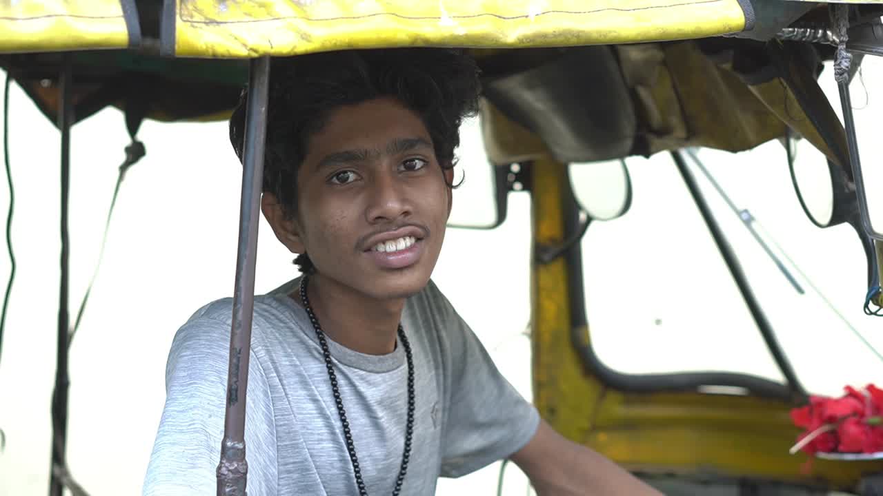 un conductor indio de tuk tuk espera una tarifa en su rickshaw, kolkata, india
