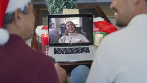 Smiling-biracial-father-and-son-using-laptop-for-christmas-video-call-with-woman-on-screen