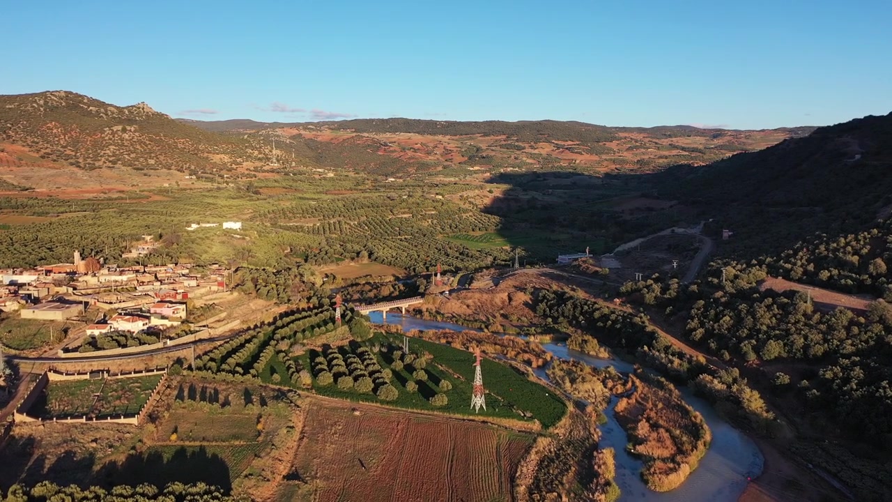 Ampio panorama aereo con drone di una valle fluviale e campi di ulivi durante l'ora d'oro nel Medio Atlante, Marocco, ideale per progetti di viaggio, natura e campagna