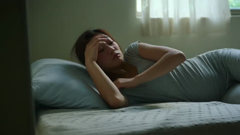 woman waking up with a headache in bed