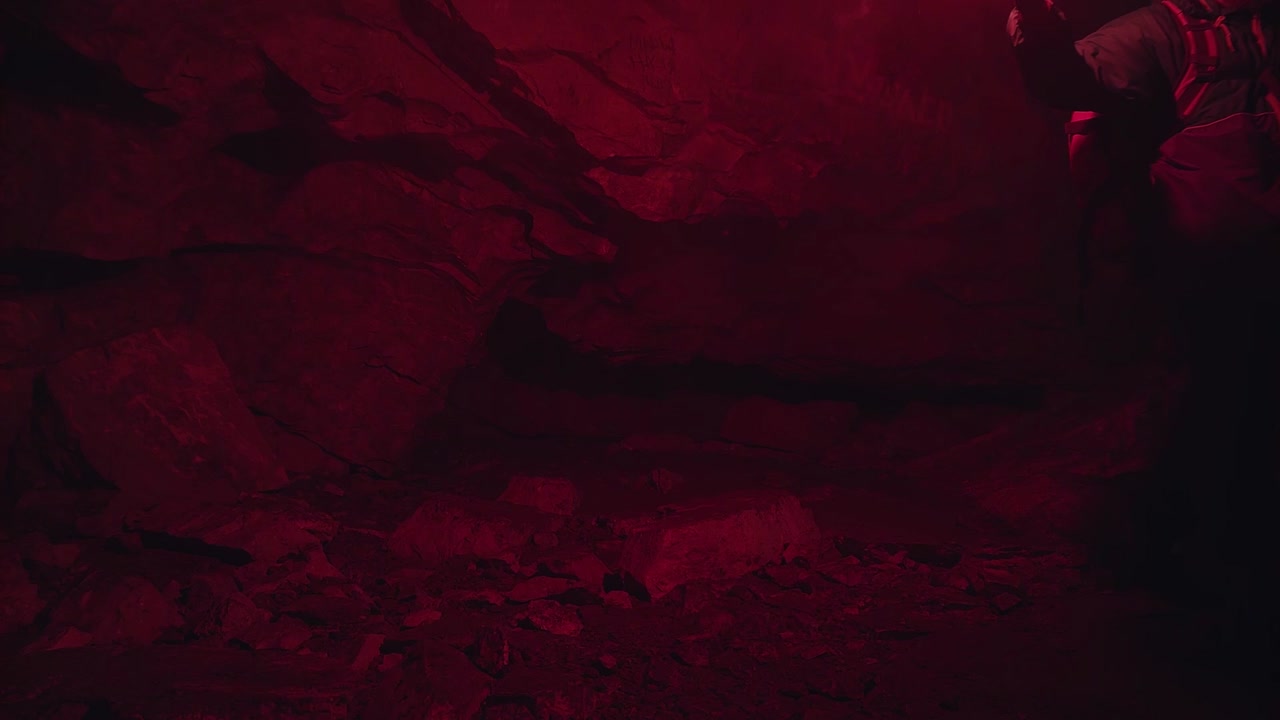 hombre con luz roja en una cueva oscura