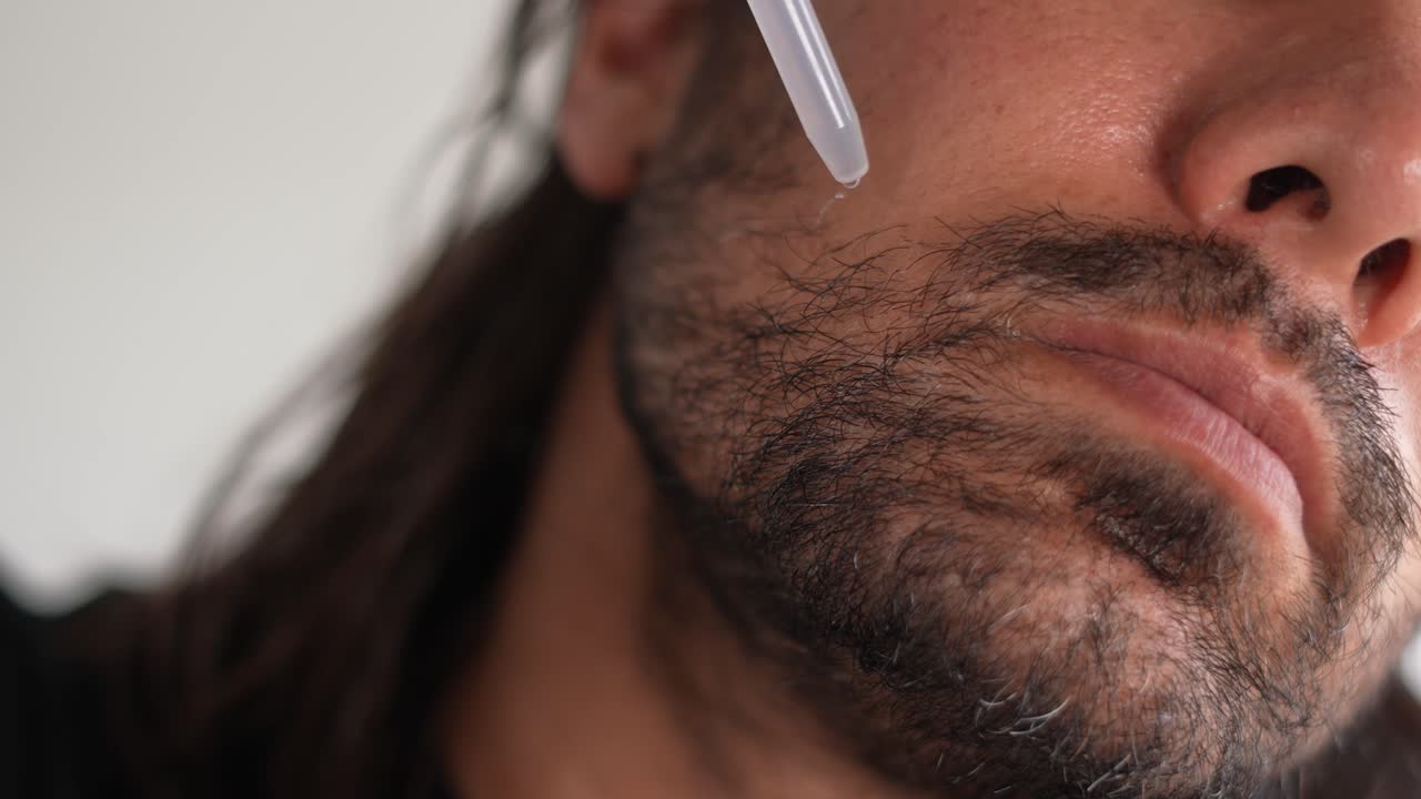 hombre aplicando minoxidil a su barba con un gotero, cuero cabelludo