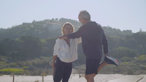 mature couple holding each others shoulders and stretching legs