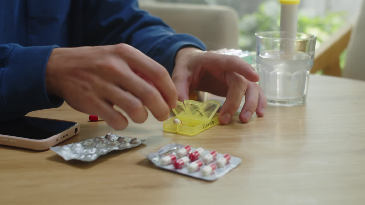Hands of Man Placing Vitamins in Pill Box