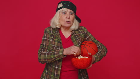 Ältere-ältere-Basketballfanfrau,-Die-Popcorn-Isst,-Eine-Siegergeste-Macht-Und-Den-Sieg-Feiert