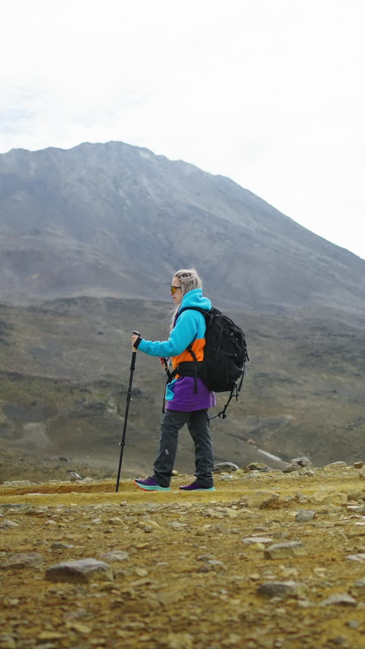 Mujer haciendo senderismo con mochila y bastones de trekking en un paisaje montañoso