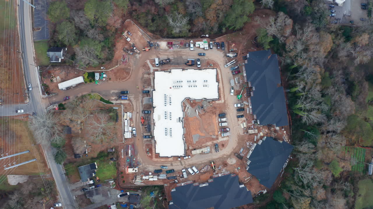 An overhead shot of construction workers and their cars parked around the work site of a new commercially zoned development on valuable real estate in the gentrified suburbs of Atlanta.