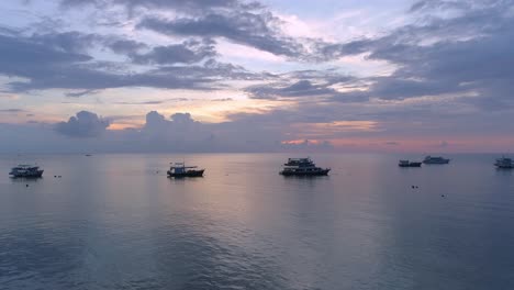 sunset over the ocean with boats