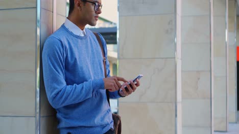 Man-using-mobile-phone-against-pillar-4k