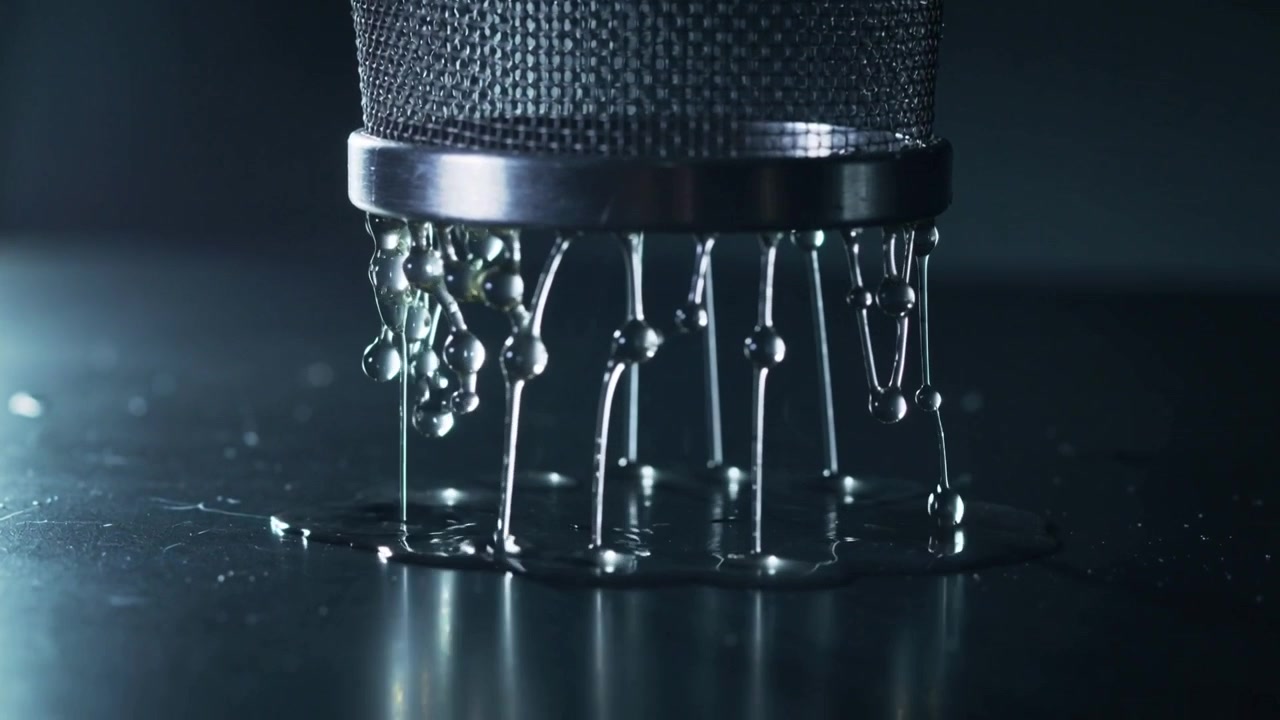 Gravity pulling metal mesh cylinder releasing viscous strands onto shiny mirror surface, left glow