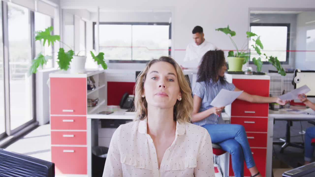 슬로우 모션으로 현대 사무실에서 책상 위에 앉아서 미소 짓는 전문 사업가