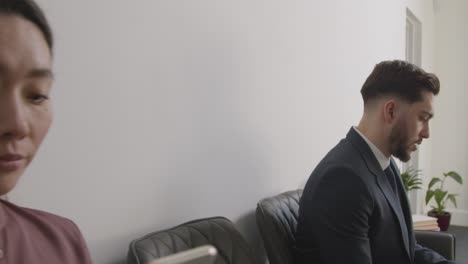 Male-And-Female-Candidates-In-Office-Waiting-For-Job-Interview-Looking-At-Mobile-Phone-And-Reading-Notes-1