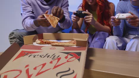 Group-Of-Gen-Z-Friends-Sitting-On-Sofa-At-Home-Gaming-And-Eating-Takeaway-Pizza-1