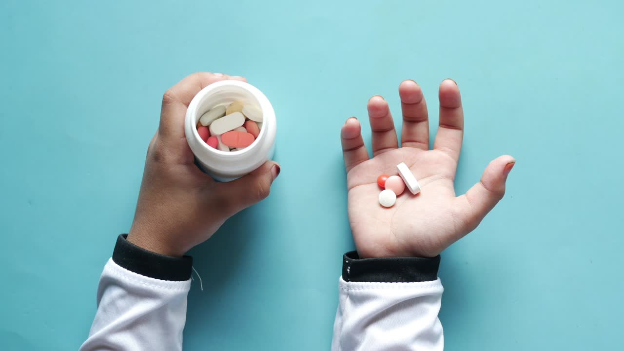 la mano del médico con pastillas y frasco de medicina