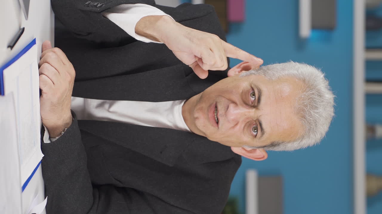 video vertical de un trabajador de oficina en casa mirando nerviosamente a la cámara.