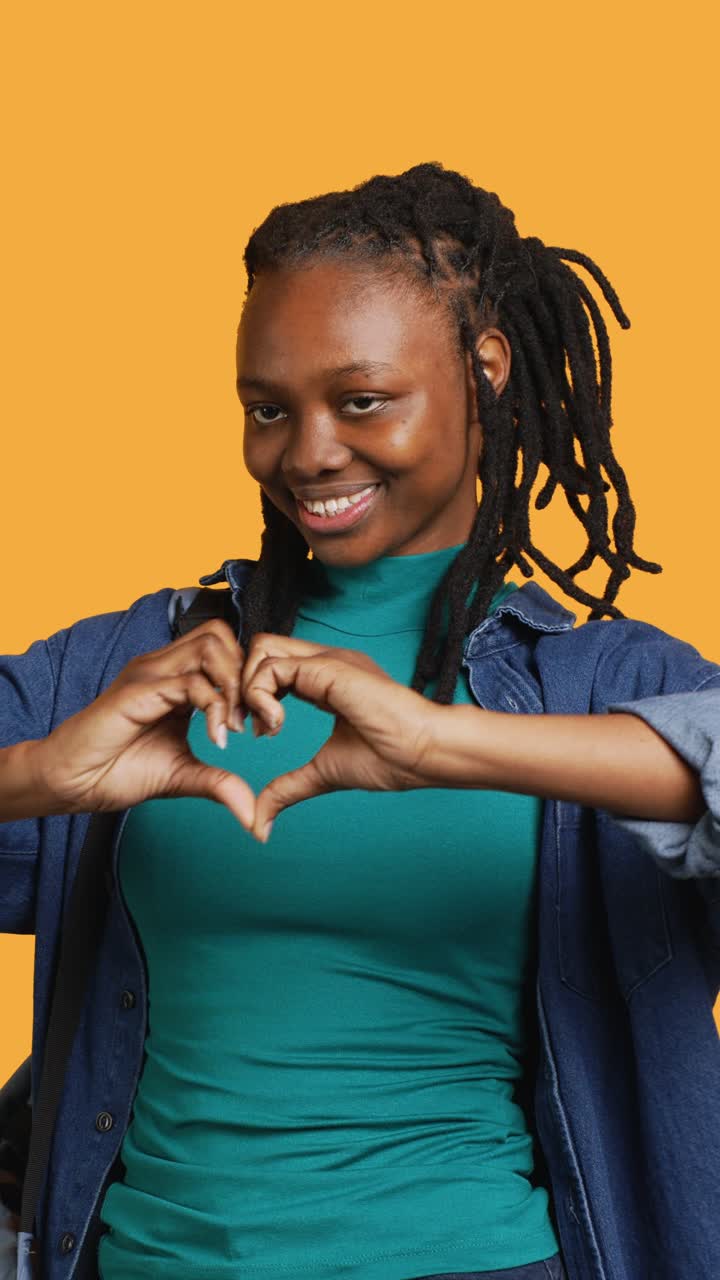 Giovane donna africana che fa un cuore con le mani e sorride