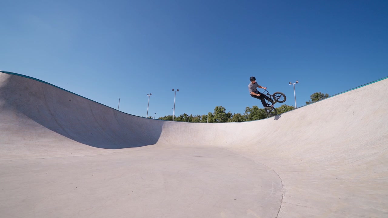 Rider di BMX che esegue un trick su una bowl di cemento in uno skatepark.